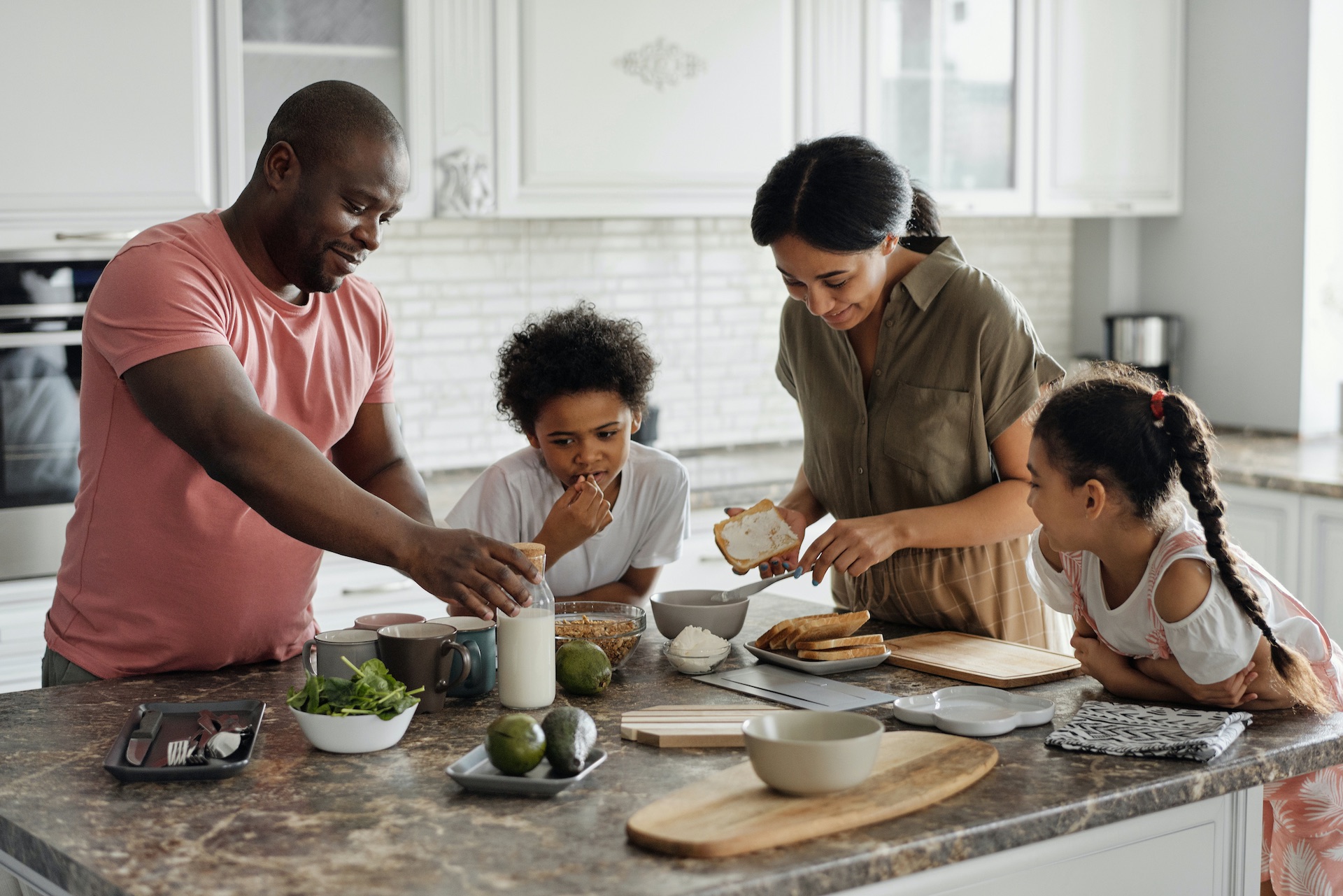 Pais reunidos com os dois filhos na cozinha a preparem a refeição